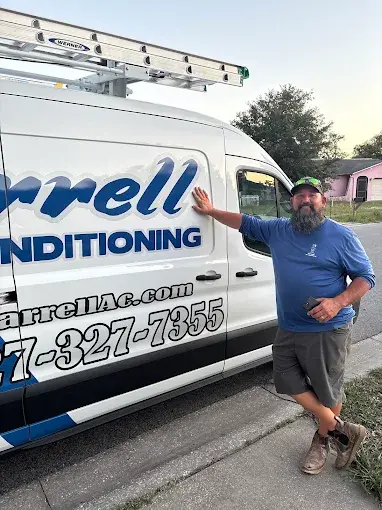 Farrell Air Conditioning technician standing beside a Farrell service van